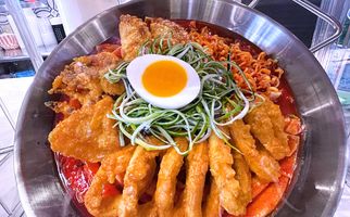 A Korean dish with noodles and an egg presented in a wok.