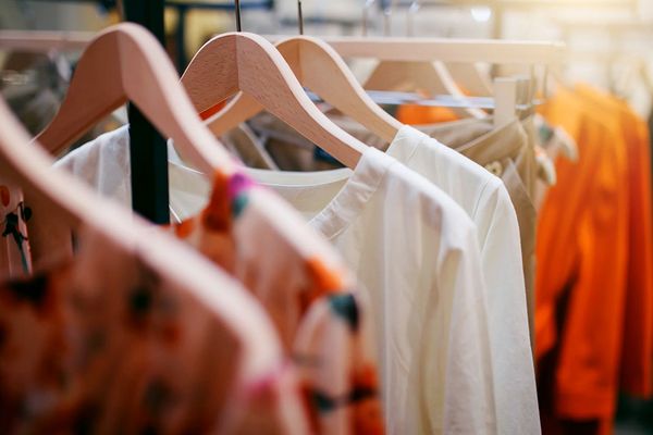 Clothing on hangars in store racks at a thrift shop.