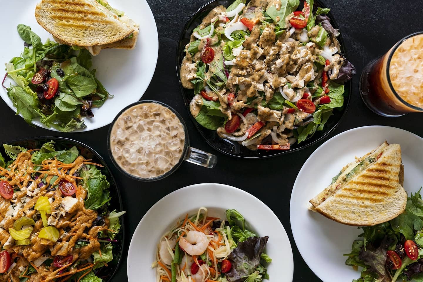 black table with salads and sandwiches