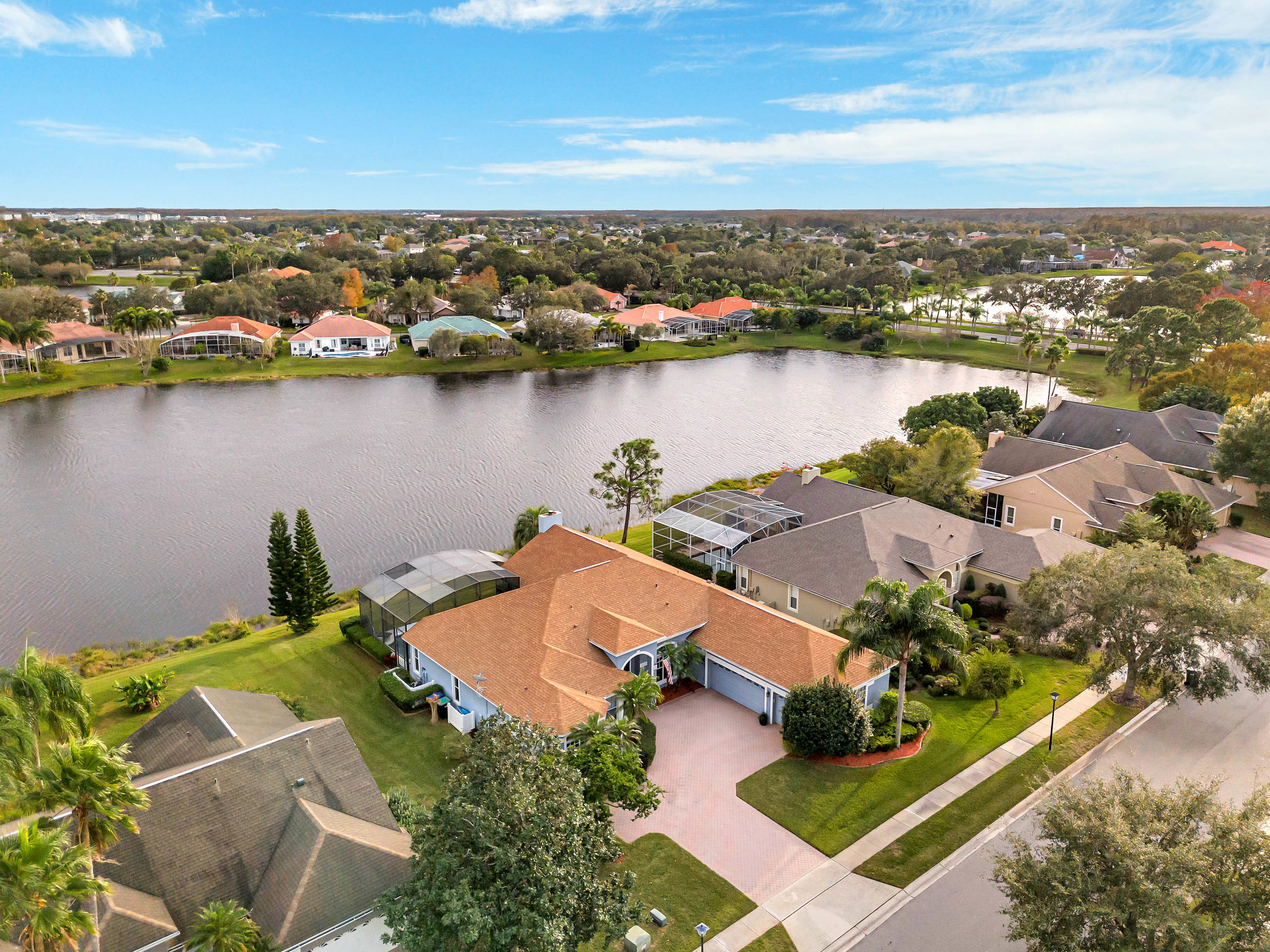 Drone shot of home with orange roof on a lake, typical of Hunter's Creek, Florida