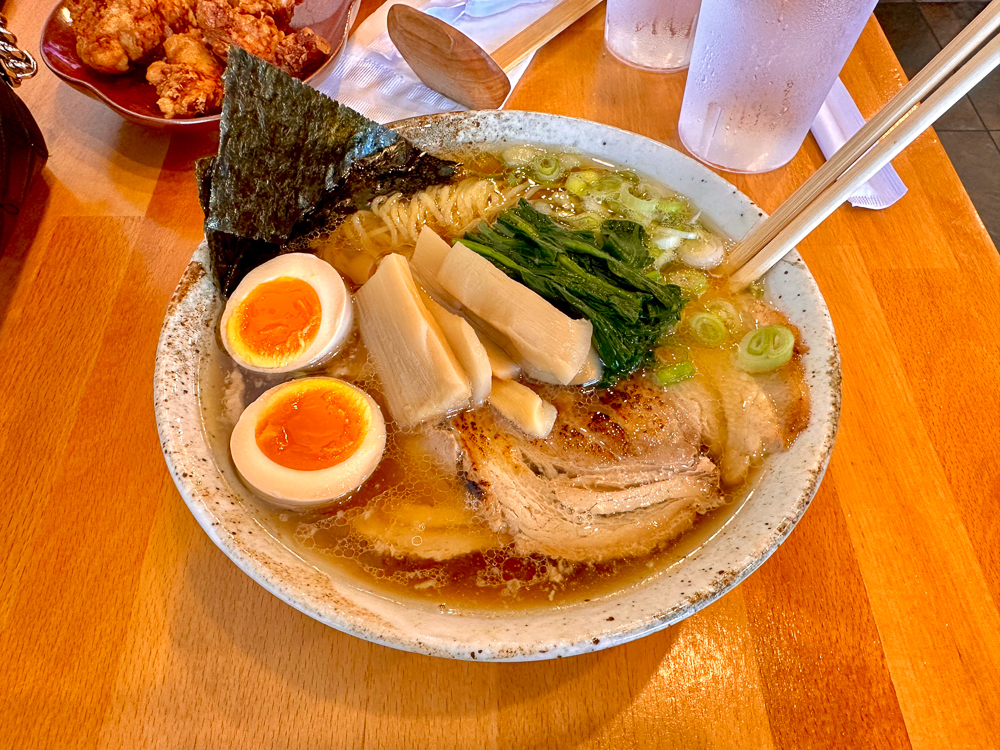 brown wood table with bowl of ramen with boiled eggs and toppings