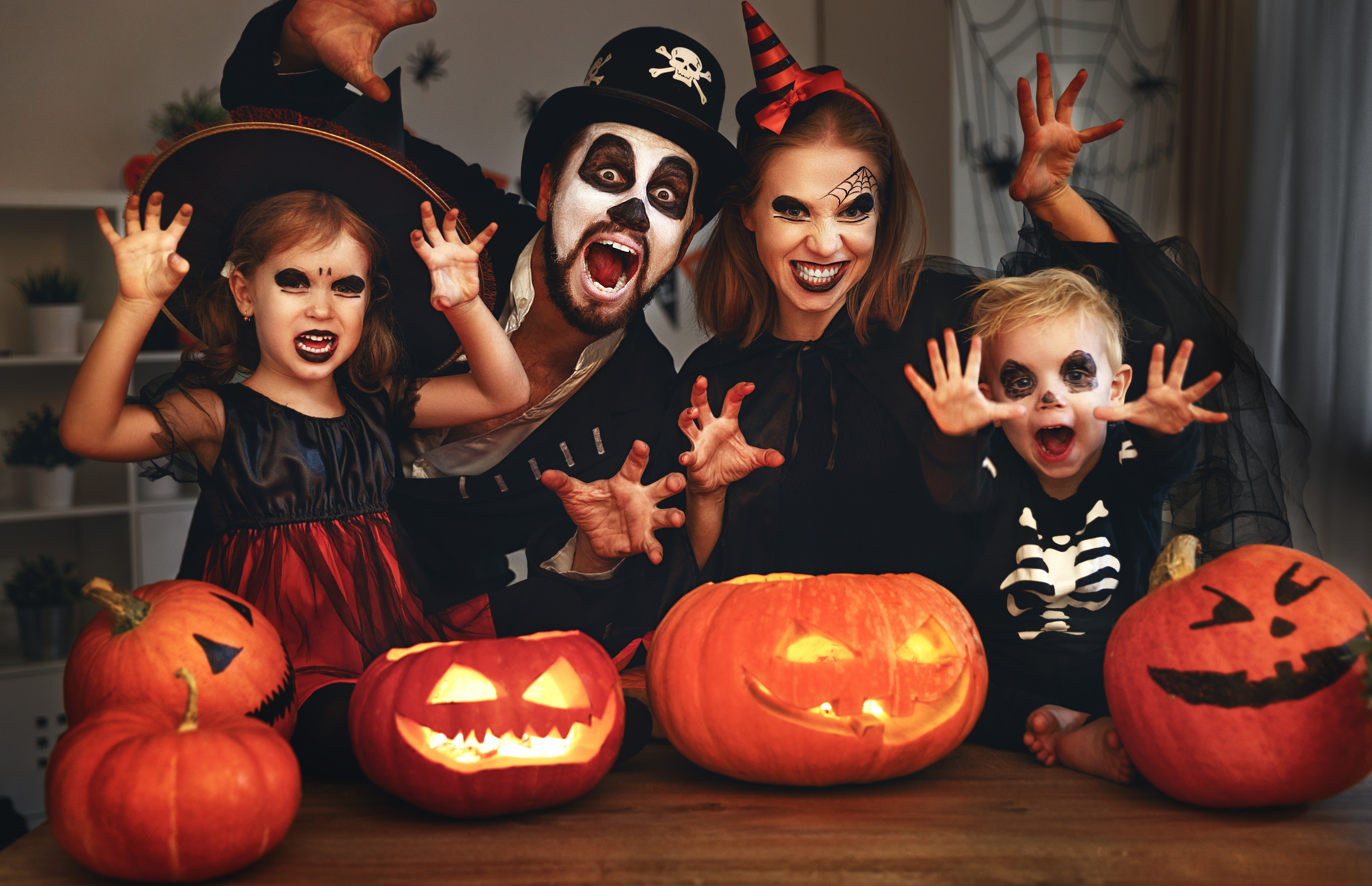family of four with halloween costumes and carved pumpkins