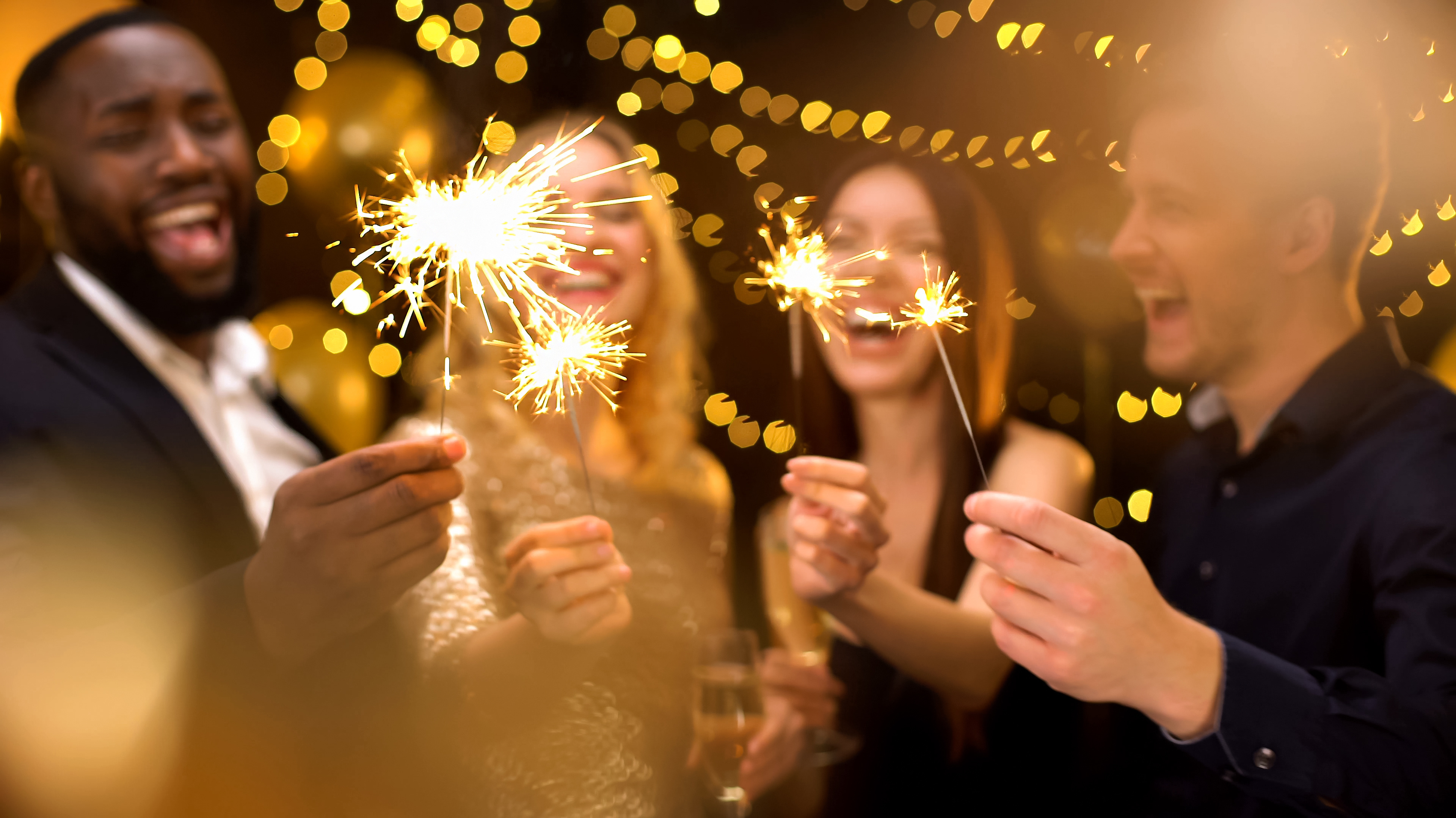four people holding sparklers with gold lights