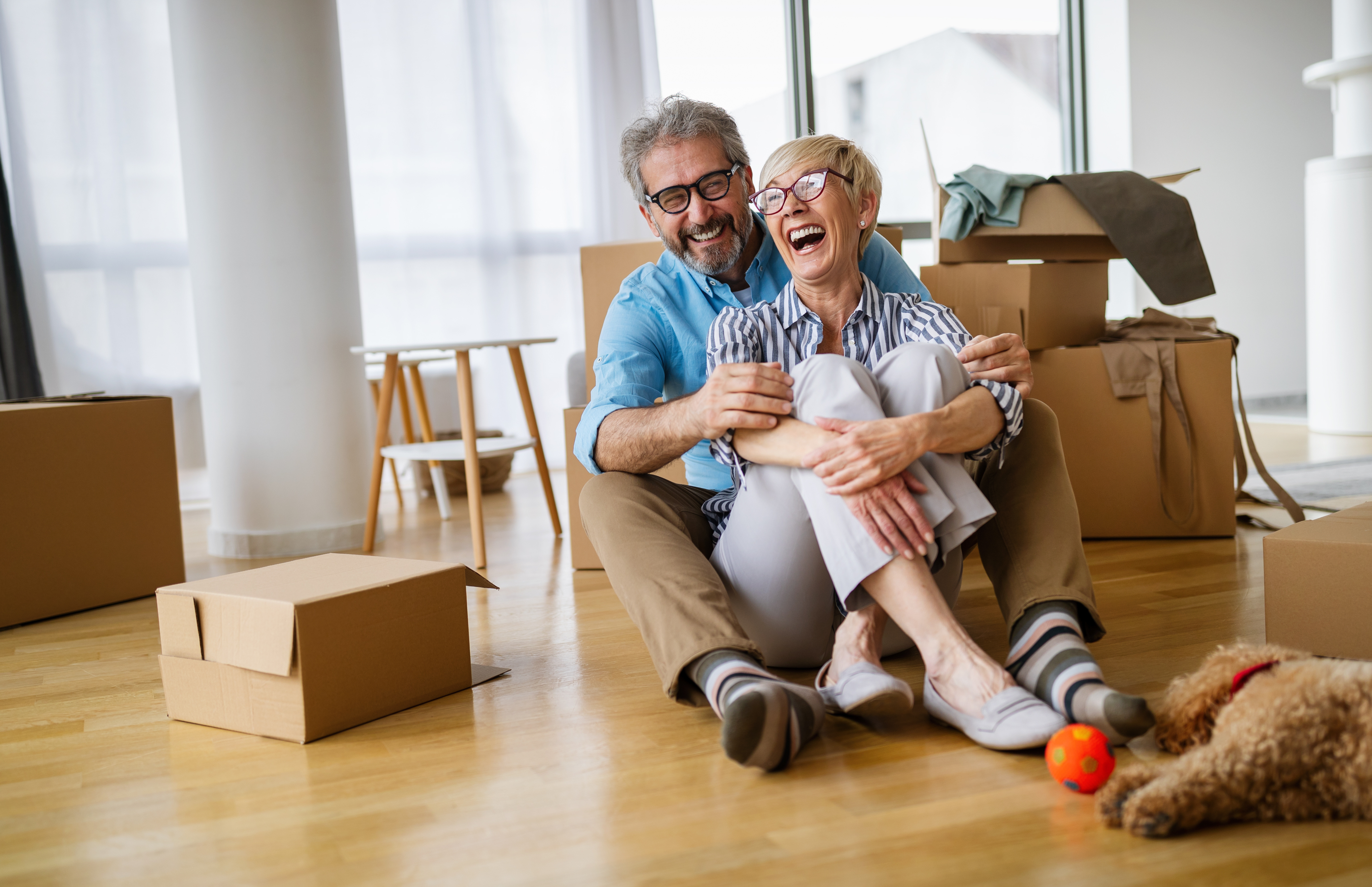 retired couple with moving boxes sitting on the floor