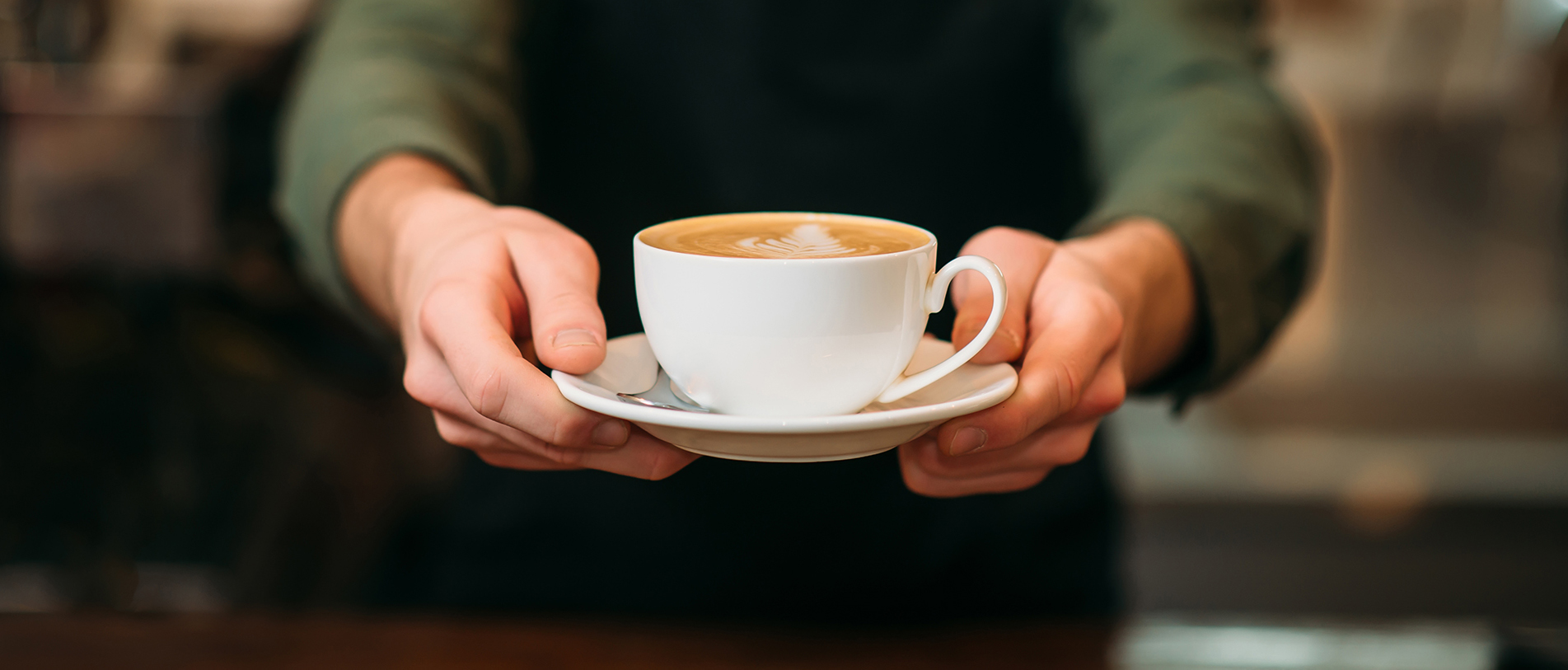 A barista serves a latte.