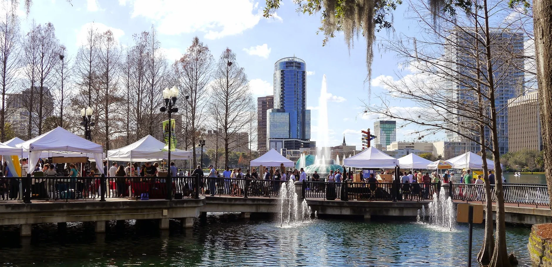 farmers market tents and downtown orlando buildings overlooking a lake