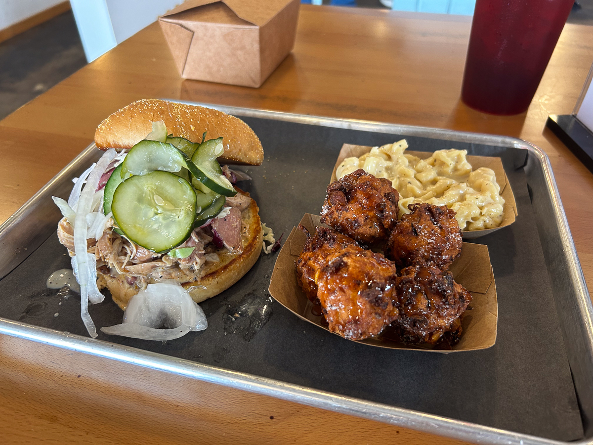 metal plate with bbq sandwich with hushpuppies and mac and cheese