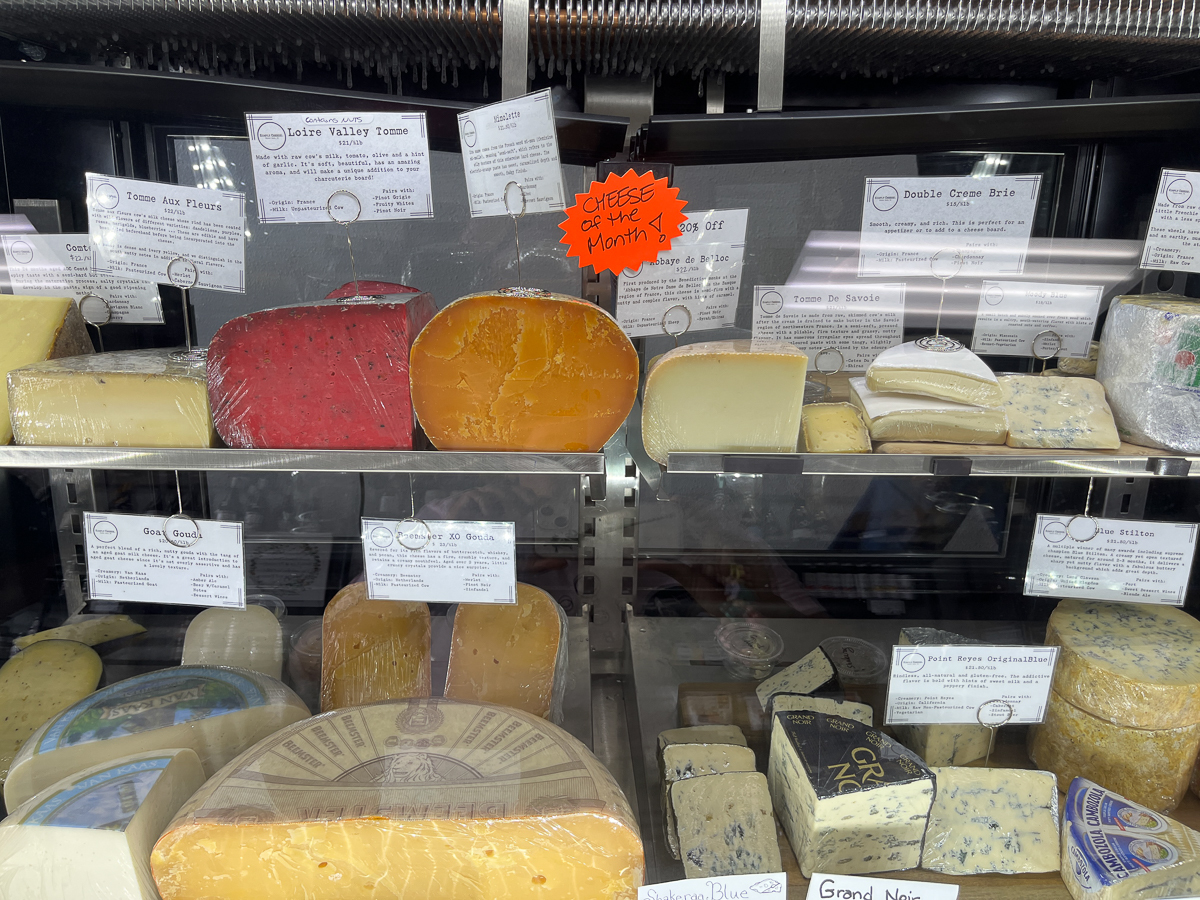 glass case with wedges of cheese and white labels
