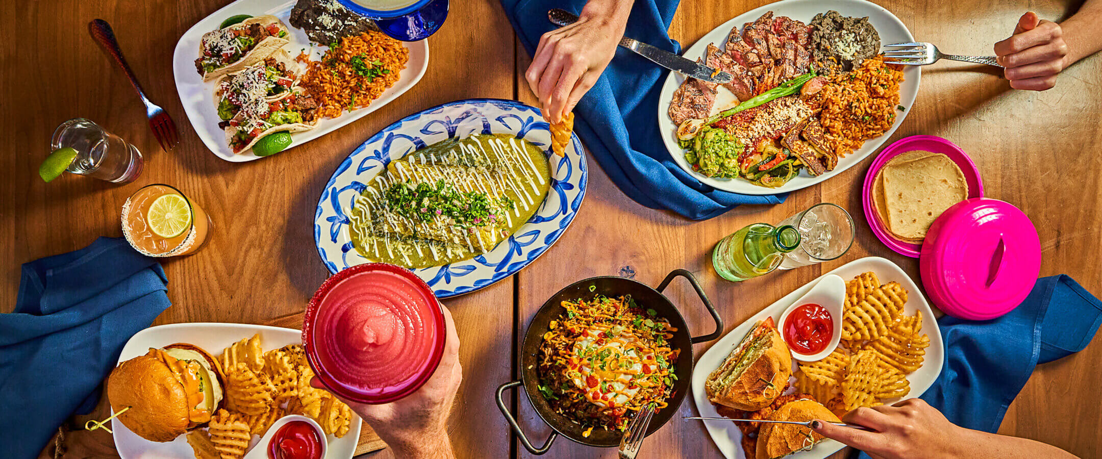 View of Mexican food on table and hands with utensils