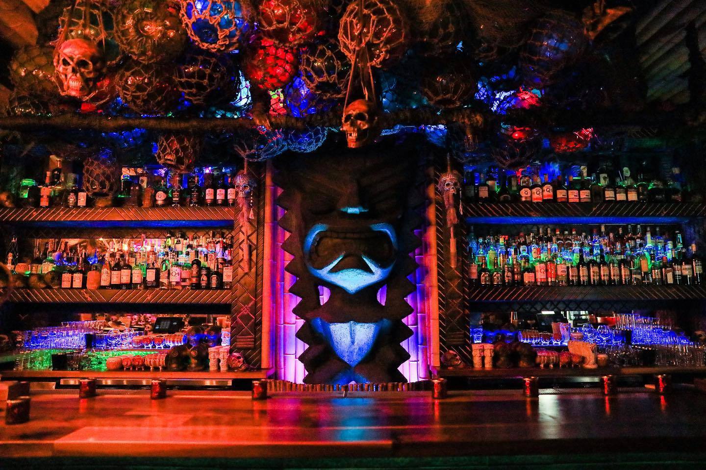tiki bar with dark lighting and colorful uplights to show decor