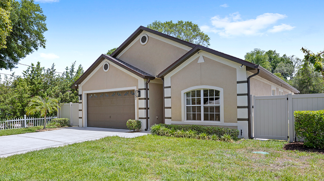 An exterior of a tan house with an attached garage.