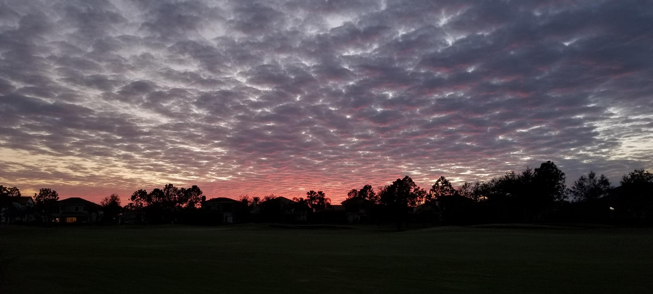 Pink sunset over Hunters Creek area golf course with silhouettes of homes