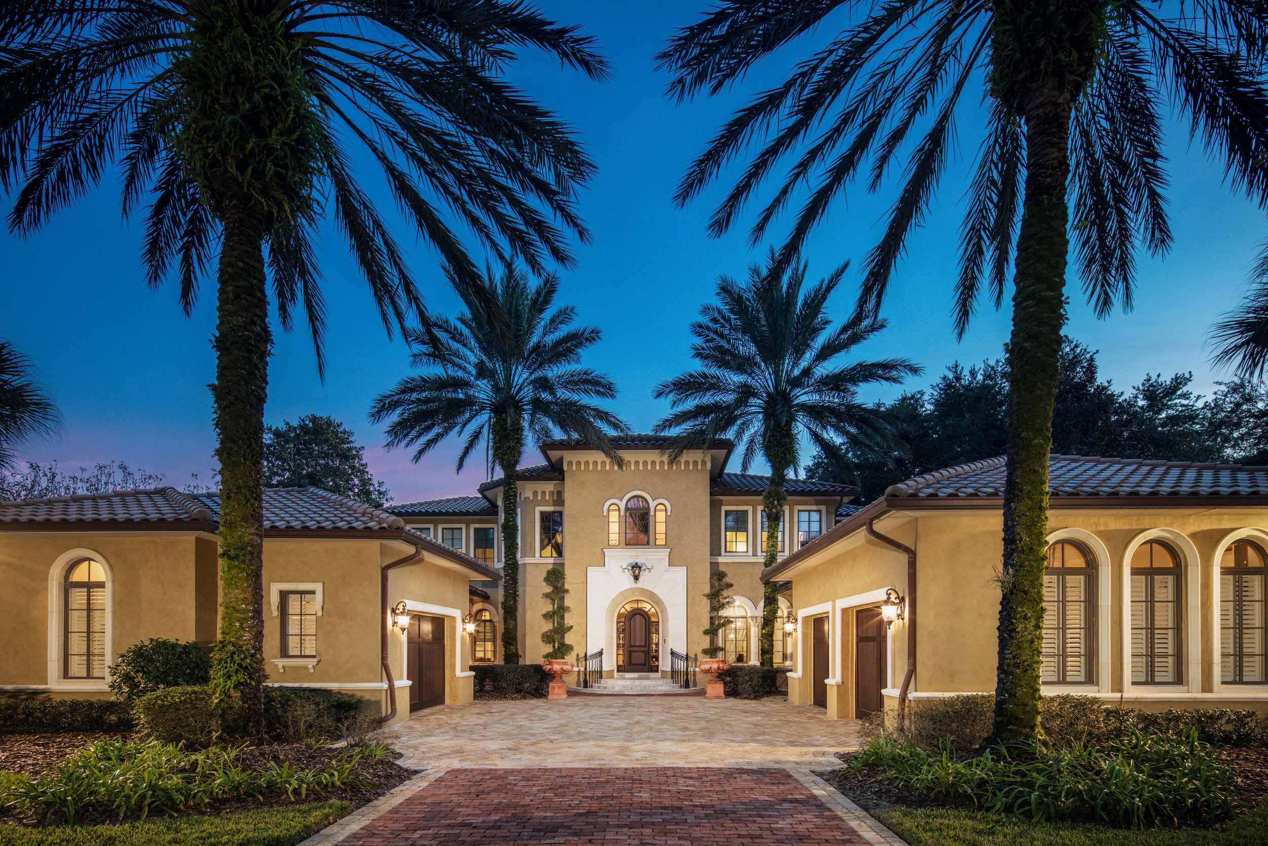 Isleworth mansion with yellow lighting and blue sky with palm trees