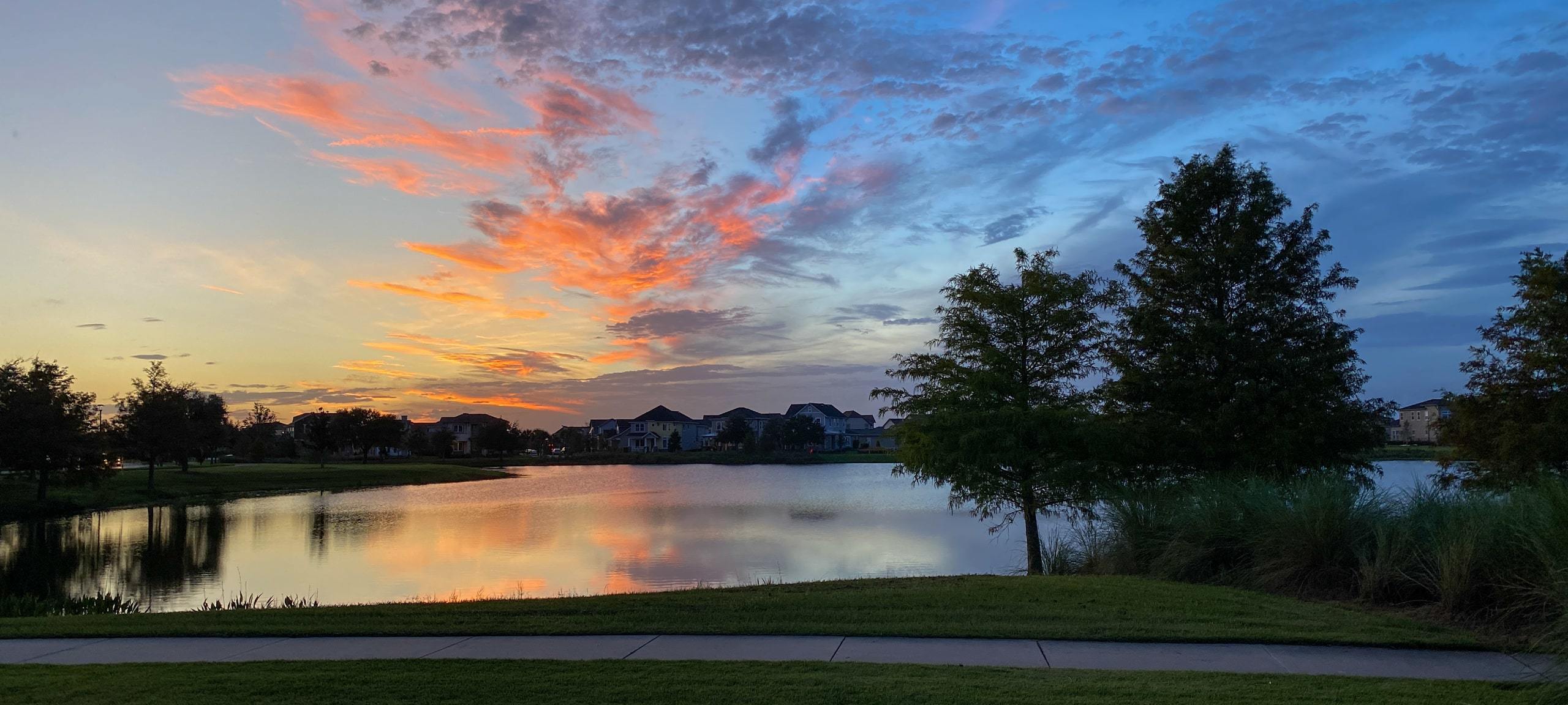 Sunset over pond in Orlando, Florida neighborhood with homes in distance